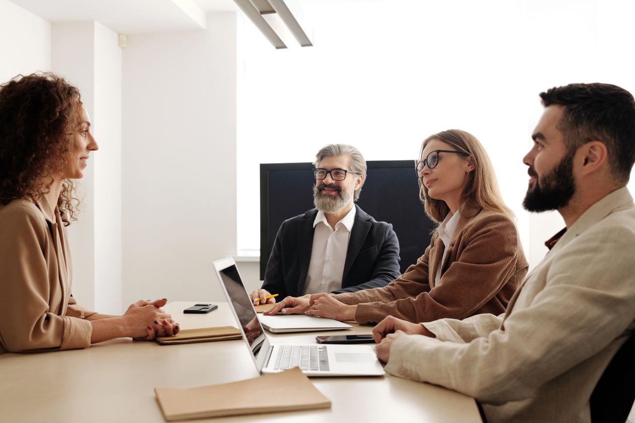 Home Group of professionals in a business meeting discussing strategies around a table in an office setting.