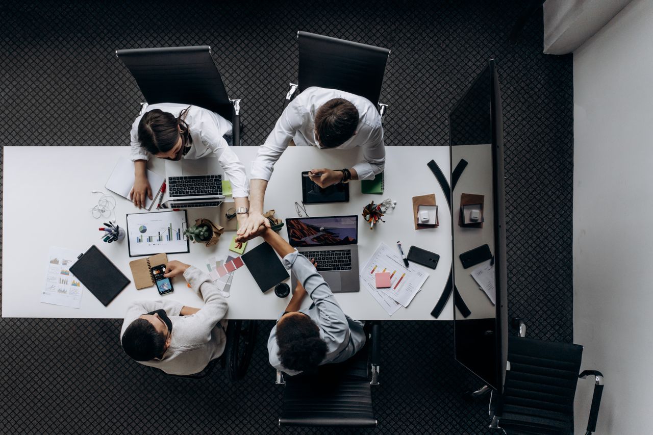 Home High angle view of colleagues collaborating around a conference table in a modern office setting.