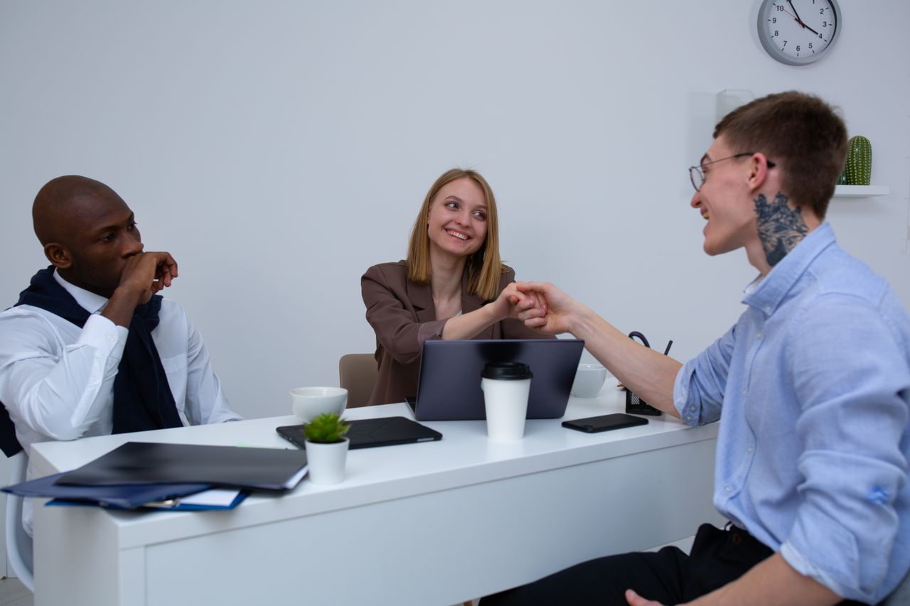 Home Three diverse colleagues in a modern office having a productive meeting, engaging with each other.